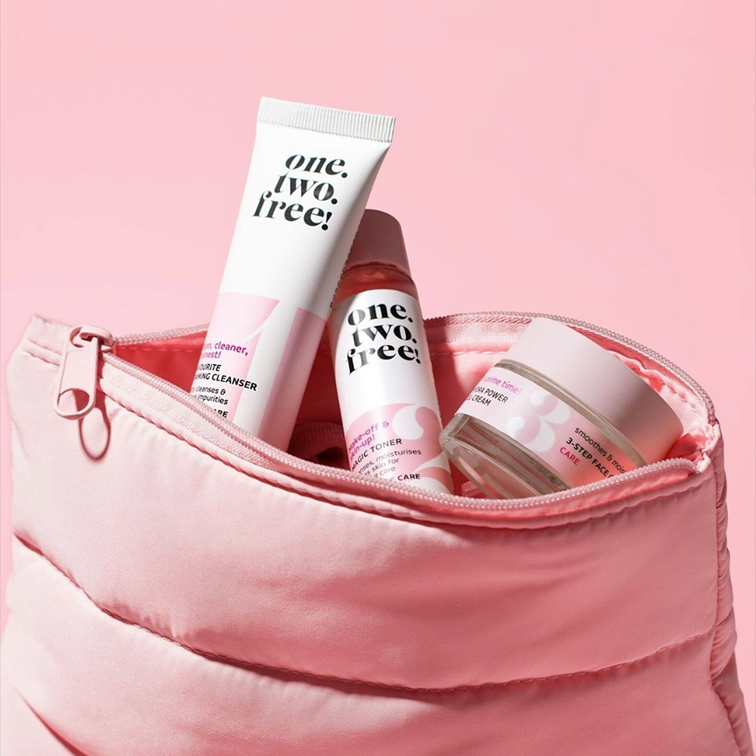 A pink cosmetic bag filled with products from one.two.free!